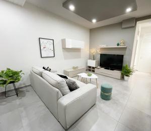 a white living room with a couch and a tv at Casa Lulu in Belpasso
