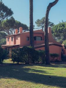 una casa rosa con árboles delante de ella en Onyria Quinta da Marinha Villas, en Cascais