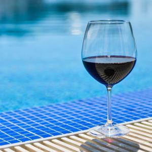 a glass of wine sitting on a table next to a pool at FLORENCE SUITES APART HOTEL in Sveti Vlas