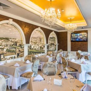 a restaurant with white tables and chairs and chandeliers at FLORENCE SUITES APART HOTEL in Sveti Vlas