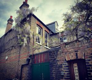 ein Backsteingebäude mit einer grünen Tür und einer Garage in der Unterkunft Campania & Jones House in London