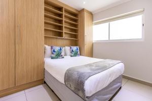 1 dormitorio con 1 cama grande con estanterías de madera en Perfect Beachfront Apartments, en Ciudad del Cabo