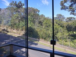 a window with a view of a road and trees at Apto Sol Poente in Canela