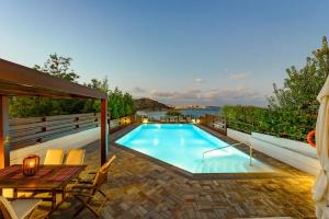 a swimming pool on a patio with a table and chairs at Agios Nikolaos Beach Villas in Agios Nikolaos