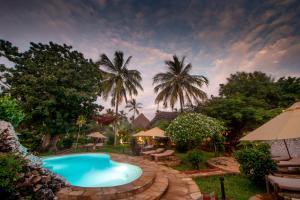 uma piscina num quintal com palmeiras em Villa Kiva Boutique Hotel em Matemwe