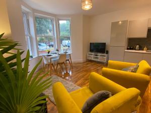 a living room with yellow furniture and a dining room at De Parys Flat 1 in Bedford in Bedford