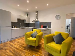 a living room with two yellow chairs and a kitchen at De Parys Flat 1 in Bedford in Bedford