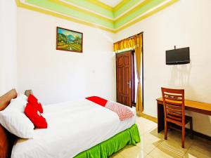 um quarto com uma cama, uma secretária e uma televisão em OYO 91564 Ayodya Guest House em Mataram