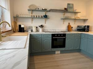 a kitchen with green cabinets and a stove at Pass the Keys The Sands Superb Newly Refurbished Beach Home in Rye