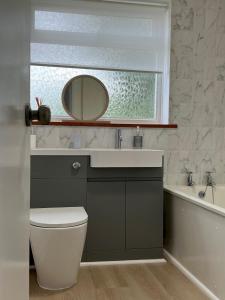 a bathroom with a sink and a toilet and a mirror at Pass the Keys The Sands Superb Newly Refurbished Beach Home in Rye