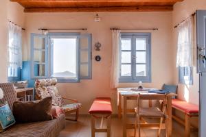 een woonkamer met een bank, een tafel en 2 ramen bij Villa Nina, dreamy little cycladic home in Amorgos in Órmos Aiyialís