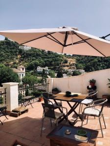 een patio met een tafel en stoelen en een parasol bij Casa Guidai in Granada
