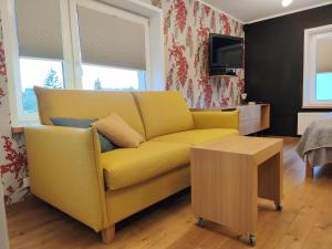 a living room with a yellow couch and a table at Arte Golf Apartment in Kuressaare