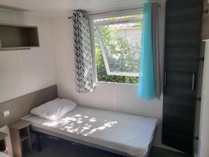 een kleine kamer met een bed en een raam bij Mobil-home L'Olivier in Fréjus