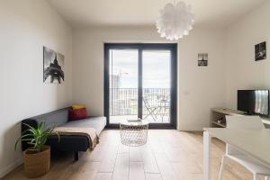 un soggiorno con divano e una grande finestra di JOIVY UpTown Flats with Balcony, Good Connection to Milan Centre a Milano
