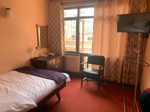 1 dormitorio con cama, escritorio y ventana en Lhasa Guest House en Katmandú