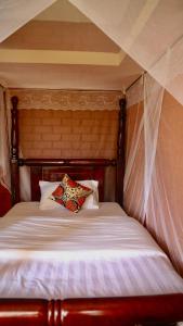een bed met een houten hoofdeinde met een kussen erop bij Sina Village in Mpigi