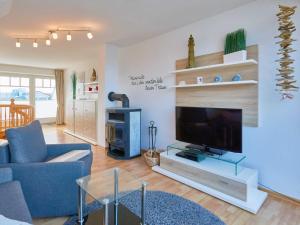 ein Wohnzimmer mit einem blauen Sofa und einem TV in der Unterkunft Apartmenthaus Jahreszeiten - Meerblick-Fewo 28 in Binz