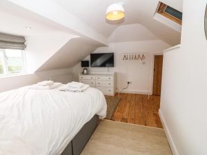 a bedroom with a white bed and a tv at Angorfa in Pwllheli