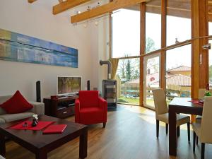 ein Wohnzimmer mit einem roten Stuhl und einem Tisch in der Unterkunft Ferienhaus Luv & Lee - Apt. 01 in Ostseebad Sellin