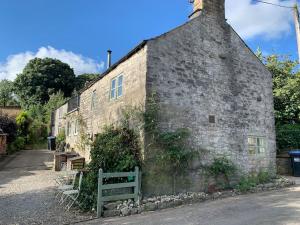 een oud stenen gebouw met een bank ervoor bij Crosse Chance Cottage - Idyllic, beautiful, traditional cottage to love - Wood burner in Taddington