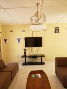 a living room with a flat screen tv and a table at Kasuda three bedrooms house in Livingstone in Livingstone