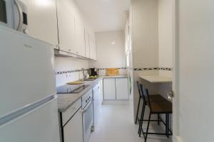a kitchen with white cabinets and a table and chairs at Apartament Rosa in Sant Pere Pescador