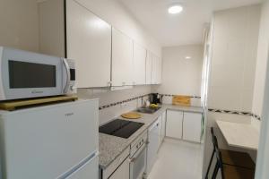 cocina blanca con armarios blancos y microondas en Apartament Rosa, en Sant Pere Pescador
