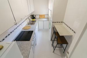 una pequeña cocina con armarios blancos y encimera en Apartament Rosa en Sant Pere Pescador