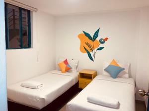 two twin beds in a room with a flower on the wall at Hostal Casa Lantana La Candelaria in Bogotá