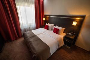 a hotel room with a large bed with red curtains at Delta In in Dzierżoniów