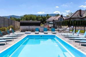 ein Schwimmbecken mit Liegestühlen und ein Schwimmbecken in der Unterkunft Apartamenty EverySky Górskie Tarasy - Kwiatowa 5-7 in Karpacz