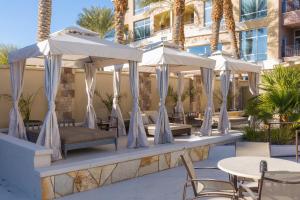 un patio avec des tables, des chaises et des parasols dans l'établissement Staybridge Suites Las Vegas - Stadium District, à Las Vegas