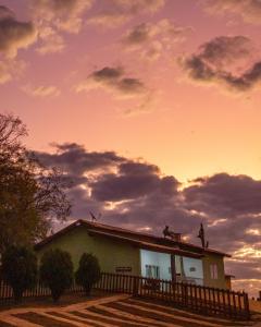 una casa con una valla delante de una puesta de sol en Paraíso Rural, en São Thomé das Letras