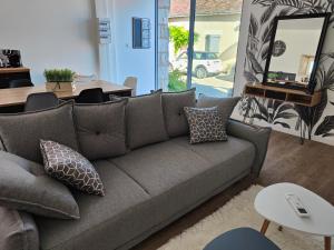 a living room with a gray couch and a table at Gîte Les Piraudières in Noyant-de-Touraine