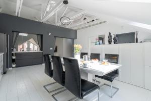 una sala da pranzo con tavolo bianco e sedie nere di Grey House a Vilnius