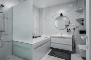 a white bathroom with a sink and a mirror at Grey House in Vilnius