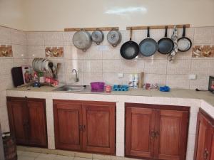 una cocina con armarios de madera, ollas y sartenes en la pared en CHAMBRES PRIVEES CLIMATISEES-DOUCHES PERSONNELLES-NEFLIX-SALON en Dakar