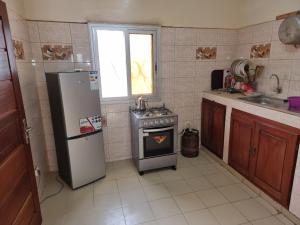 a kitchen with a refrigerator and a stove and a window at CHAMBRES PRIVEES CLIMATISEES-DOUCHES PERSONNELLES-NEFLIX-SALON in Dakar