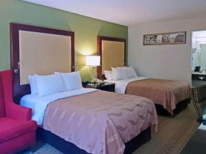 a hotel room with two beds and a red chair at Super 8 by Wyndham Morganton in Morganton