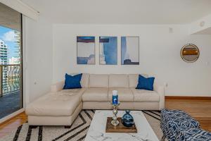 uma sala de estar com um sofá branco e almofadas azuis em Lovely condo with city & ocean views. Sleep up to 6 people! em Miami