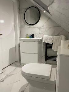 a white bathroom with a toilet and a sink at Cheerful 4 Bedroom luxury house with free parking in Quinton
