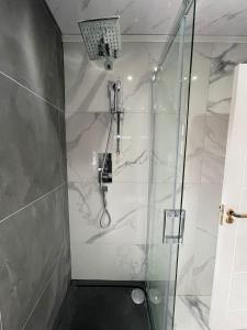 a shower with a glass door in a bathroom at Cheerful 4 Bedroom luxury house with free parking in Quinton