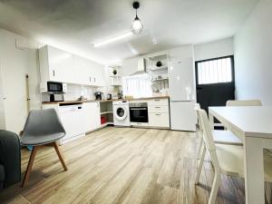 eine Küche mit weißen Schränken sowie einem Tisch und Stühlen in der Unterkunft Apartamento “El Cauce” en Sierra de Gredos - La Vera - WIFI in Madrigal de la Vera