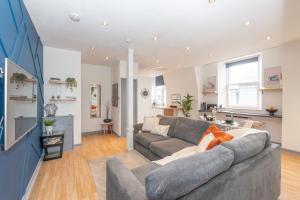 a living room with a gray couch and a kitchen at Vibrant City Centre Living in Aberdeen