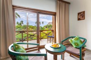 a living room with a table and chairs and a balcony at Zanzibar Queen Hotel in Matemwe