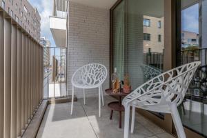 een balkon met 2 witte stoelen en een tafel bij City at Sea - Modern 1 bedroom apartement in Oostende