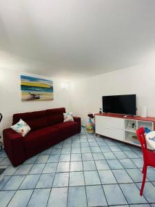 sala de estar con sofá rojo y TV en La Casetta di Sasá, en Procida