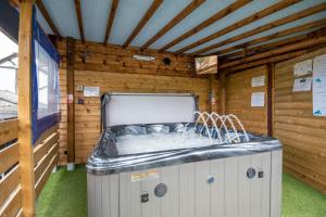 bañera de hidromasaje en una cabaña con pared de madera en Welsh Row House, en Llandegla