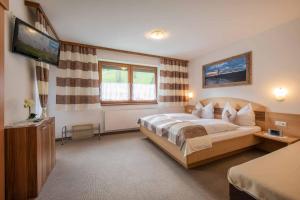 a bedroom with a large bed and a flat screen tv at Gästeheim Krößbach in Neustift im Stubaital